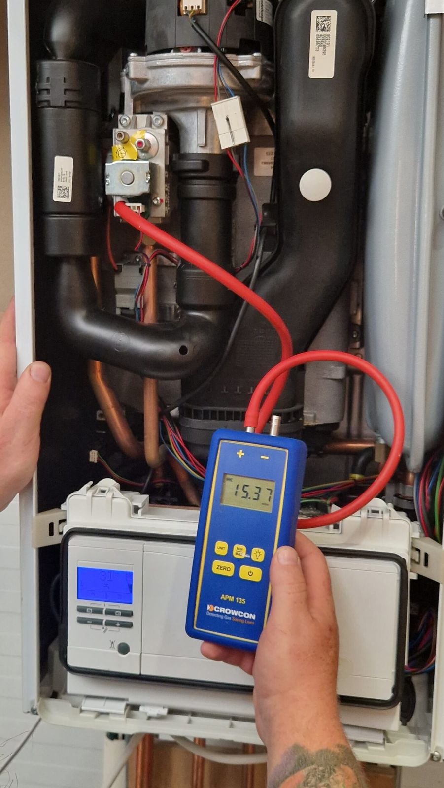 Engineer checking gas pressure on an open boiler with a digital manometer