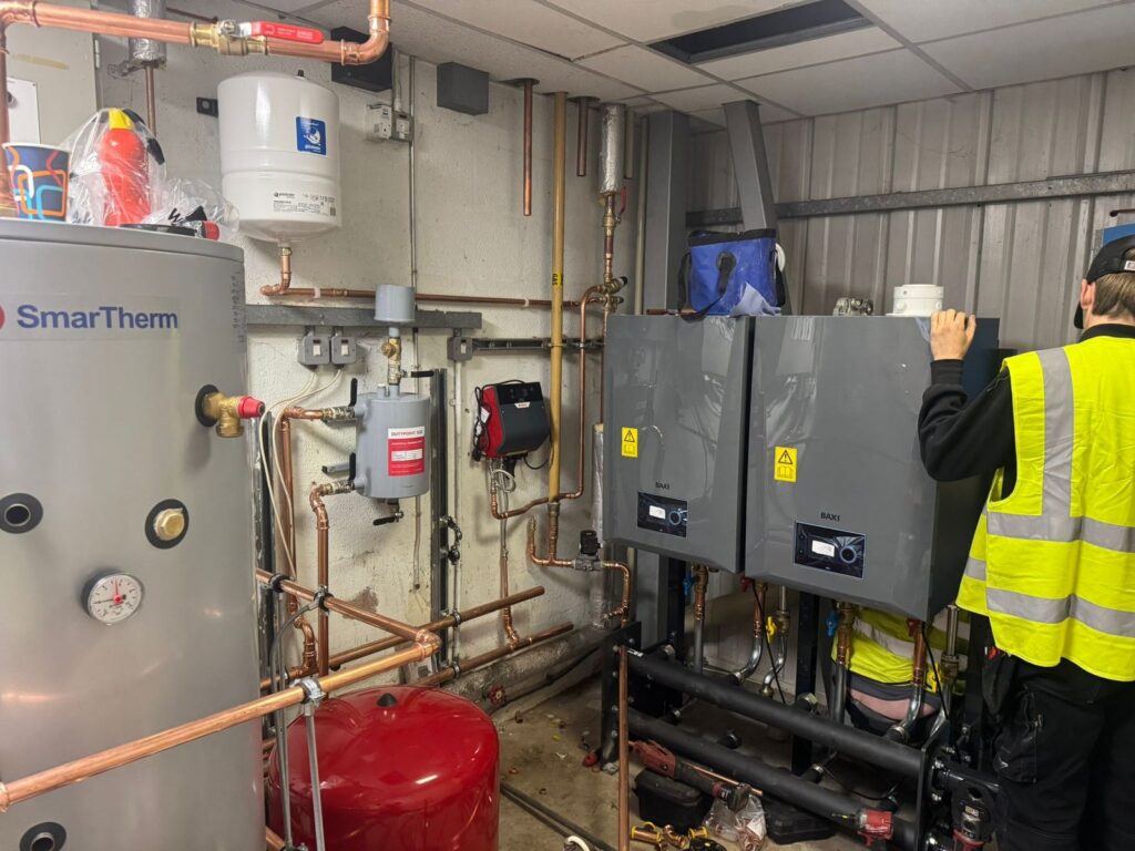 Plant room with two wall-mounted boilers, a hot water cylinder and expansion vessels
