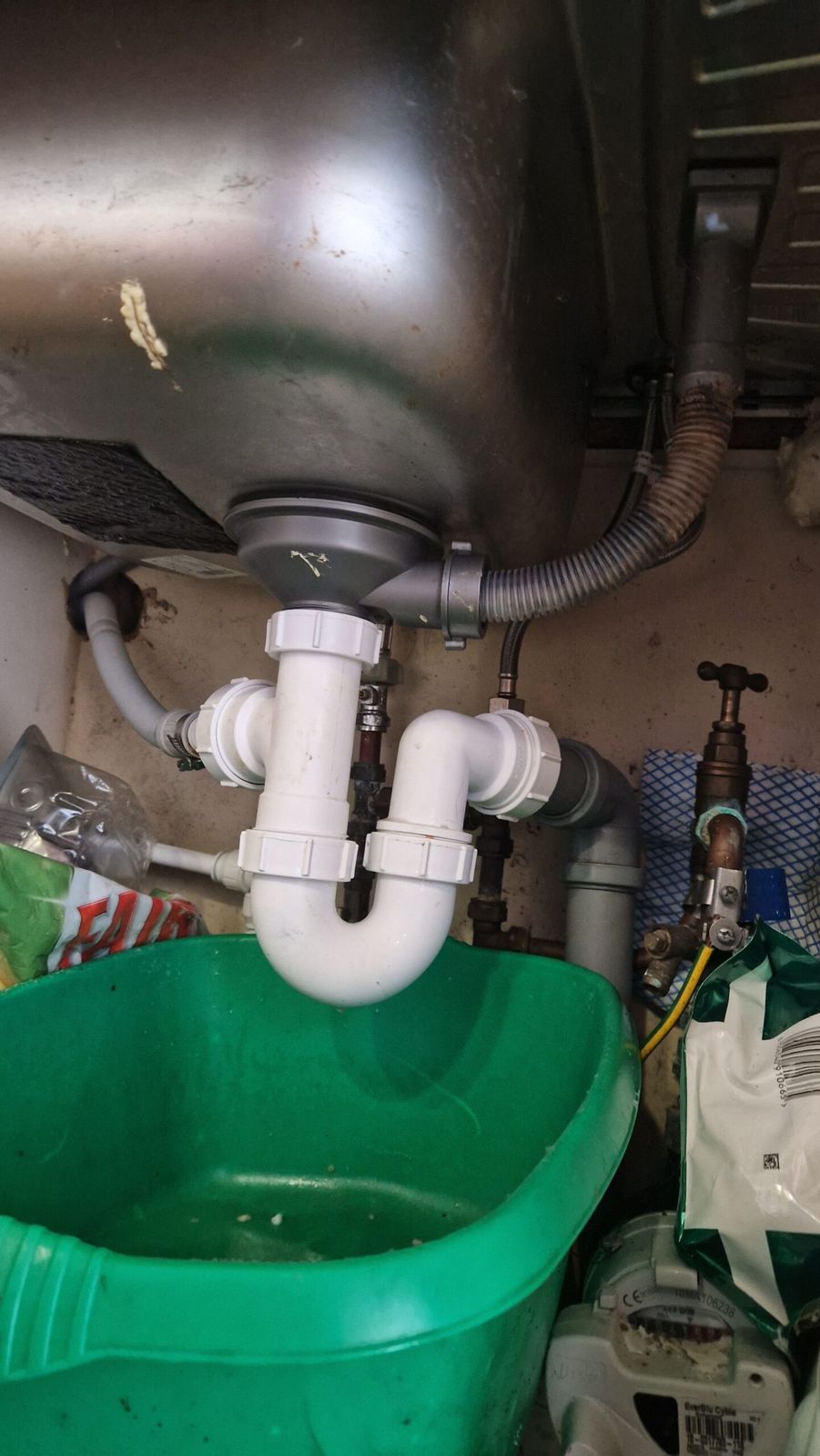 New white plastic waste trap fitted under a kitchen sink